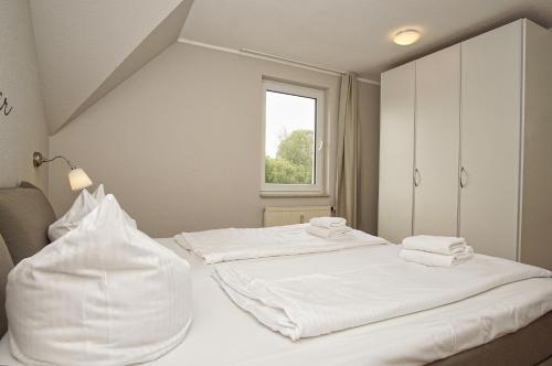 two white beds in a room with a window at strandnah mit Balkon, gratis Nutzung vom AHOI Erlebnisbad und Sauna in Sellin - Strandhaus Mönchgut FeWo16 in Lobbe