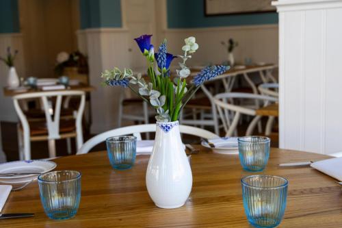 a white vase with blue flowers on a wooden table at Plesners Badehotel in Skagen