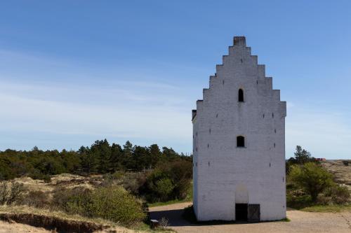 an old white building on the side of a hill at Plesners Badehotel in Skagen