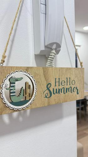 a sign that reads hello summer hanging from a phone at Vala Mar Apartments by Four C in Hamallë