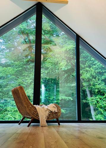 a wicker chair in a room with a large window at Joli Chalet in Râşnov