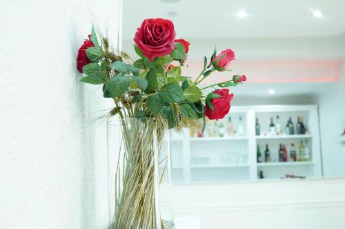 a vase filled with red roses on a wall at Bee Queen Hotel in Marina di Varcaturo
