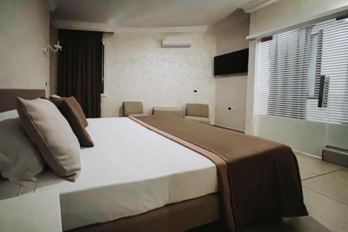 a bedroom with a large bed and a window at Bee Queen Hotel in Marina di Varcaturo