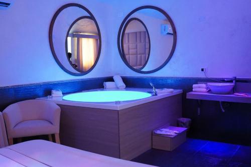 a bathroom with a tub and two round mirrors at Bee Queen Hotel in Marina di Varcaturo