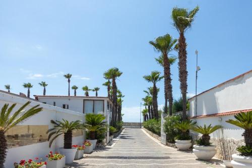 a sidewalk lined with palm trees and plants at Bee Queen Hotel in Marina di Varcaturo