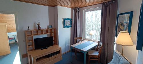 a living room with a table and a television and a desk at Huus Am Streek Padd in Cuxhaven