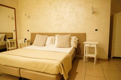 a bedroom with a bed with white sheets and pillows at Bee Queen Hotel in Marina di Varcaturo