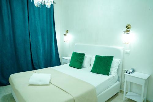a bedroom with a white bed with green pillows at Bee Queen Hotel in Marina di Varcaturo