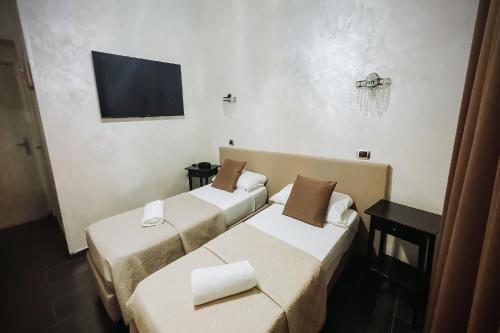 two beds in a room with a tv on the wall at Bee Queen Hotel in Marina di Varcaturo