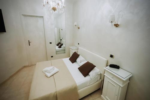 a white bedroom with a bed and a mirror at Bee Queen Hotel in Marina di Varcaturo