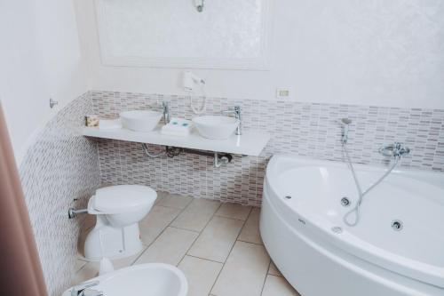 a bathroom with a tub and a toilet and a sink at Bee Queen Hotel in Marina di Varcaturo