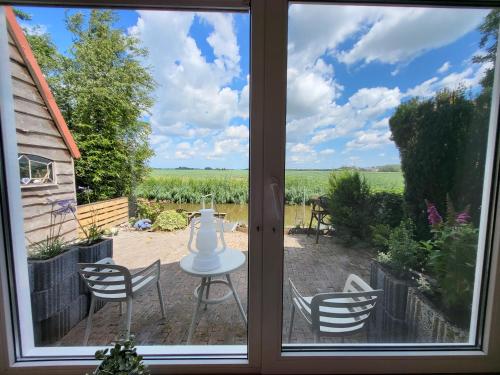 a window view of a patio with a table and chairs at Appartement 1 met uitzicht op de waterkant van Op de Roemte in Baflo
