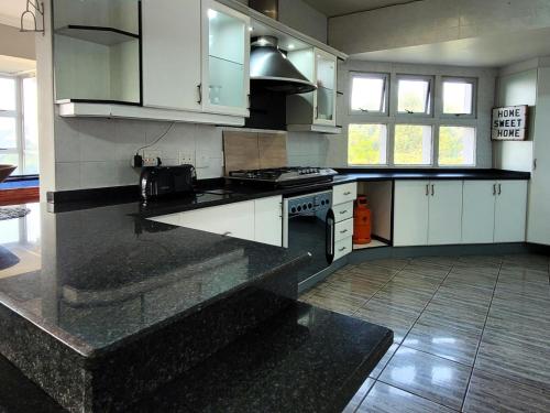 a kitchen with white cabinets and a black counter top at LookOut Ramsgate in Ramsgate
