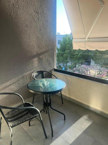 a table and two chairs in a room with a window at Vala Mar Apartments by Four C in Hamallë