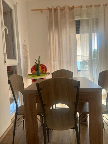 a dining table and chairs in a room with a table and a window at Vala Mar Apartments by Four C in Hamallë
