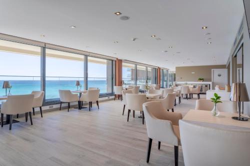 a restaurant with white chairs and tables and the ocean at Melia Alicante in Alicante