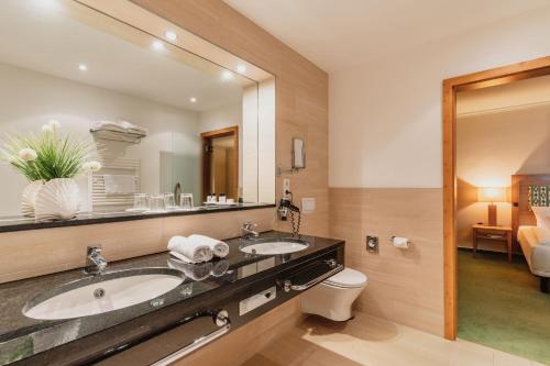 a bathroom with two sinks and a large mirror at IFA Graal-Müritz Hotel & Spa in Graal-Müritz