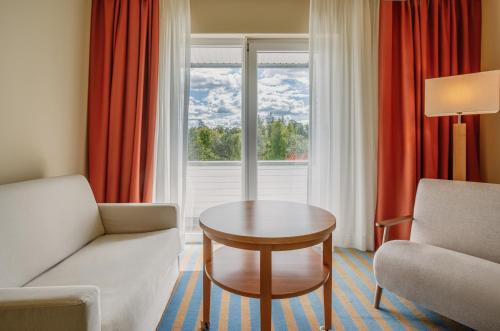 a living room with a couch and a table and a window at IFA Graal-Müritz Hotel & Spa in Graal-Müritz