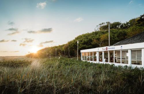 a building with the sun setting in the background at IFA Graal-Müritz Hotel & Spa in Graal-Müritz