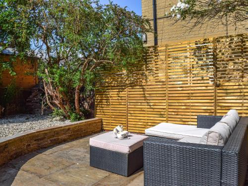 eine Terrasse mit zwei Korbstühlen und einer Katze auf einem Tisch in der Unterkunft Yorkshire Cottage in Clayton West