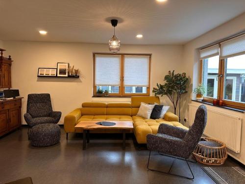 ein Wohnzimmer mit einem gelben Sofa und Stühlen in der Unterkunft Ferienhaus für 6 Personen ca 108 m in Plauen, Sachsen Vogtland in Plauen