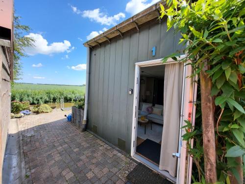 a gray shed with a door open and a patio at Appartement 1 met uitzicht op de waterkant van Op de Roemte in Baflo