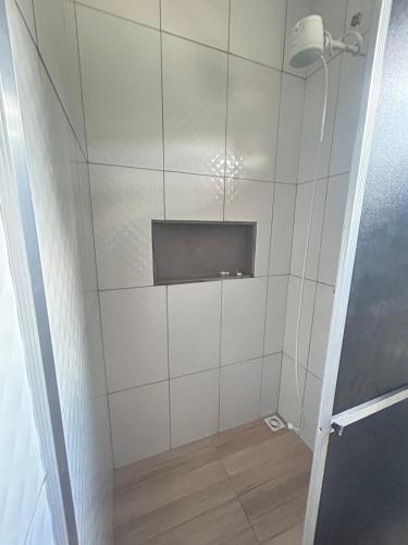 a bathroom with a white tiled wall with a tv at Micro casa Maju in Cascavel