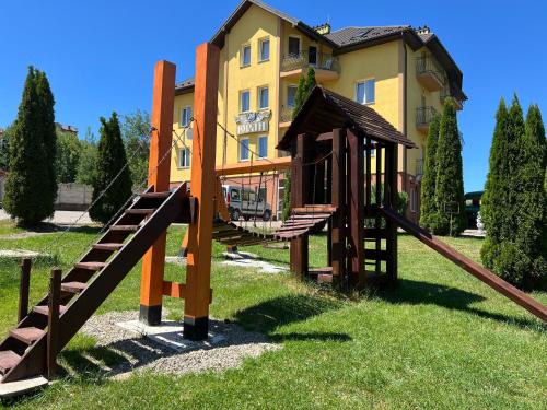 a wooden playground in front of a building at Вілла ЮРАН Східниця in Skhidnitsa
