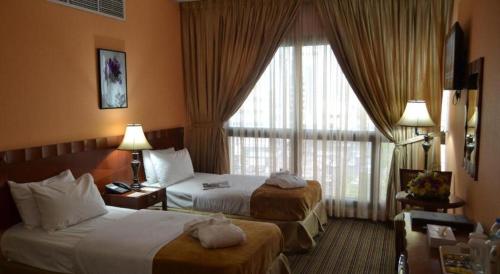 a hotel room with two beds and a window at Dancenter Top Star Heritage Village in Abu Dhabi
