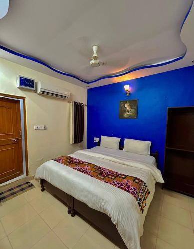 a bedroom with a blue wall and a bed at Golden Marigold Hotel in Jaisalmer