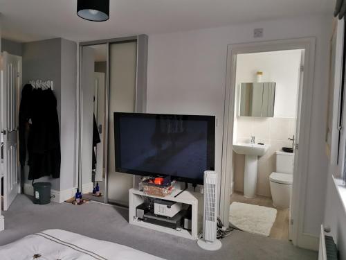 ein Wohnzimmer mit einem TV und einem Badezimmer in der Unterkunft The Grange Cute Modern Stay in Gerrards Cross
