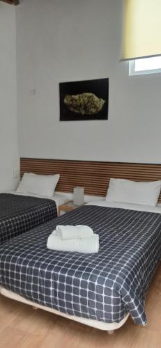 two beds in a bedroom with a blue and white blanket at sunset lodge in Las Manchas