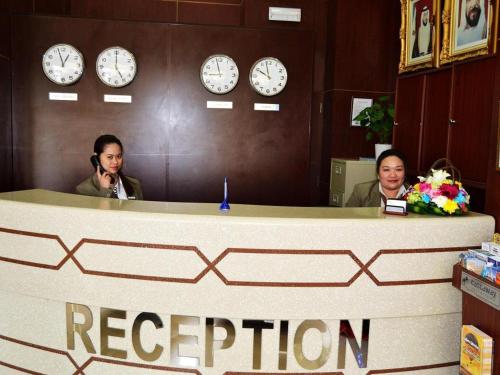 two women in an office with clocks on the wall at Belvilla Top Stars Hotel Near Gold Souk in Abu Dhabi