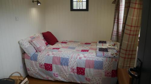 スランリグにあるShepherds Hut at Rhyd y Galenのベッドルーム(キルト付きのベッド付)