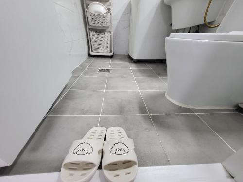 two slippers on the floor of a bathroom with a toilet at Renovated two rooms with natural light - Guwoldong in Incheon