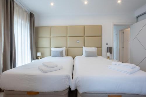 two beds in a hotel room with white sheets at Edificio Luisa Premium in Velas