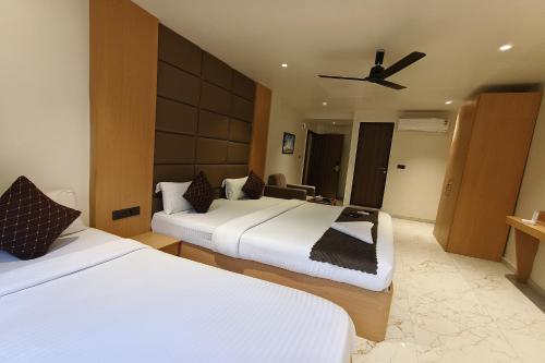 a hotel room with two beds and a ceiling fan at The Golden Arc in Pune