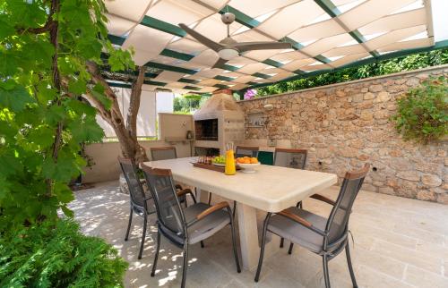 a patio with a table and chairs and a stone wall at Casa ol'Bol - Modern Apartment with Seaview and Private Large Backyard in Bol