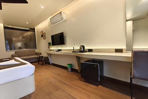 a hotel room with a desk with a tv and a couch at The Golden Arc in Pune