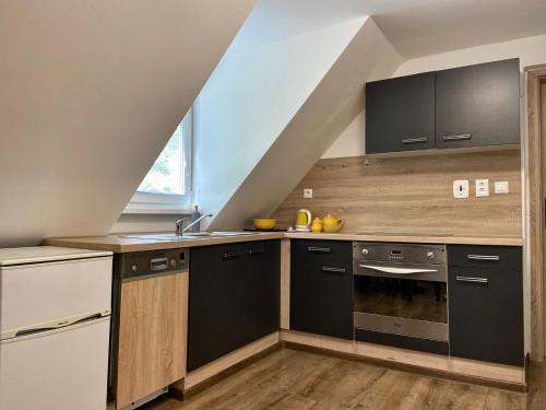 a kitchen with black and white appliances in an attic at Apartmán Zelený dom 43 in Banská Štiavnica
