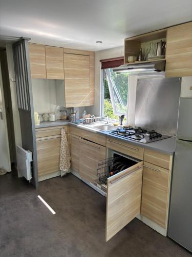a kitchen with wooden cabinets and a stove top oven at Mobile-home dans un camping in Chorges