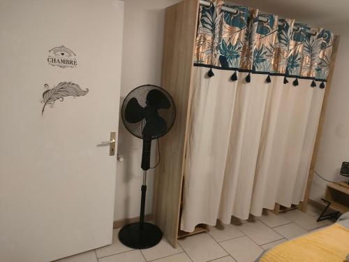 une pièce avec un ventilateur à côté d'un rideau dans l'établissement Le Jardin des Mazades - Cosy T2 - Parking - Wifi Fibre Gratuit, à Champcevinel