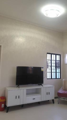 a living room with a flat screen tv on a white cabinet at Peaceful Haven in Hermosa, Philippines - Entire House for Rent in Hermosa