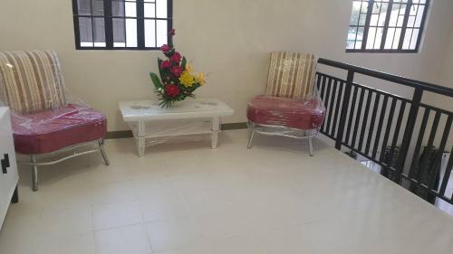 a room with two chairs and a table with flowers at Peaceful Haven in Hermosa, Philippines - Entire House for Rent in Hermosa