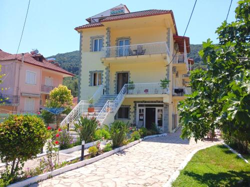 a large yellow house with stairs in a yard at Oliva Suites & Apartments in Parga