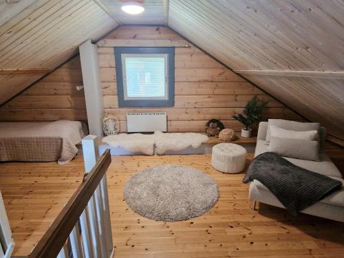 a attic room with a bed and a couch and a rug at Villa Ylähonka - 6 hlö, Himos Honkaranta in Himos