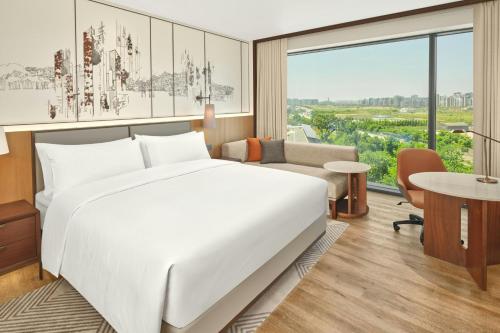 a hotel room with a bed and a large window at Courtyard by Marriott Pyeongtaek in Pyeongtaek
