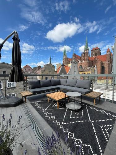 a couch and tables on a balcony with a city at VIU Indigo Apartments in Gdańsk
