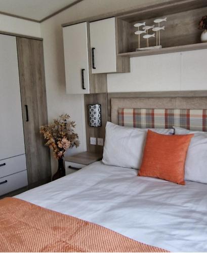 a bedroom with a white bed with an orange pillow at Edgewater Retreat- Pet Friendly-On Award winning Hoburne Devon bay in Goodrington