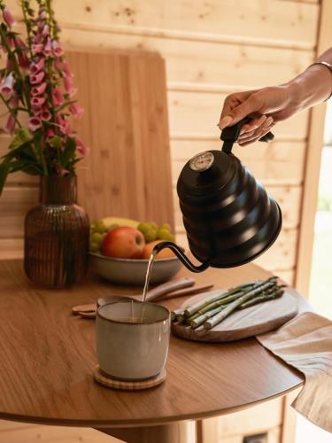 a person pouring coffee into a tea pot on a table at Sosnowy Szept in Karpacz